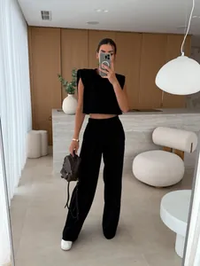 Woman wearing a black padded shoulder sleeveless top and wide-leg pants fashion set