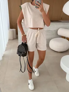 Model wearing a casual beige padded shoulder top and matching shorts in a modern room