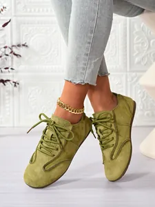 Close-up of olive green suede lace-up casual shoes for women with stylish gold anklet