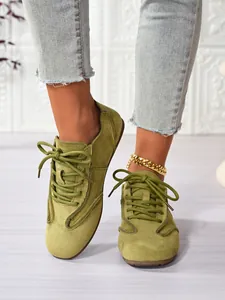 Close-up detail of stylish olive green suede lace-up casual sneakers for women.