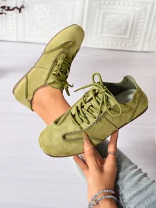 Close-up of lime green suede casual flat sneakers with laces, showing soft texture.