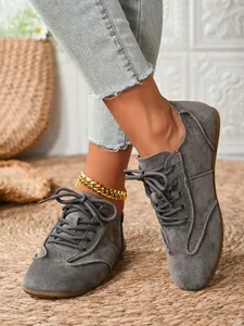 Women's gray suede lace-up shoes, close-up lifestyle view on woven mat