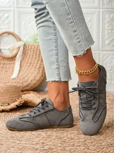 Close-up of the stitching and lace-up texture on grey suede-like casual women shoes.