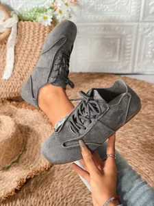 Close-up detail of grey suede lace-up casual sneakers with a minimalist lifestyle design