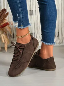 Detailed view of stylish brown suede lace-up casual shoes worn with a gold anklet