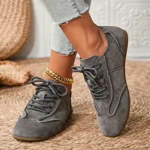 Comfortable grey suede lace-up casual flat shoes for women on a woven rug