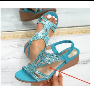 Close-up of Bohemian wedge sandals with turquoise rhinestone floral patterns