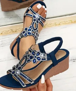 Close-up of bohemian wedge sandals featuring intricate blue rhinestone flower patterns