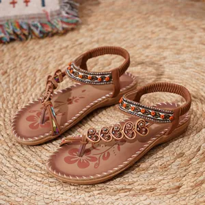 Close-up of Bohemian flat sandals with floral beads and ethnic embroidery on woven mat.