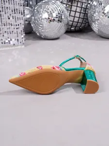 Close-up detail of stylish green metallic heel and floral fabric on pointed-toe pumps