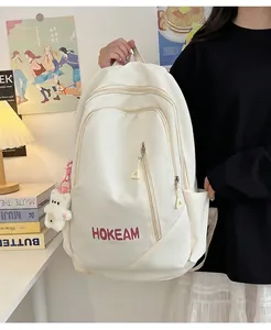 Detailed view of white high-capacity school backpack with HOKEAM logo and bear charm.