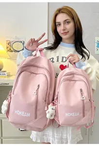 Minimalist pink school backpacks in two different sizes shown with a model for scale