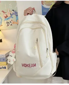 Détail d'un sac à dos blanc minimaliste pour étudiant avec un joli pendentif ours