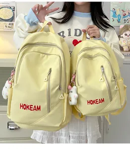 Front view of two yellow minimalist student backpacks featuring cute bear keychains