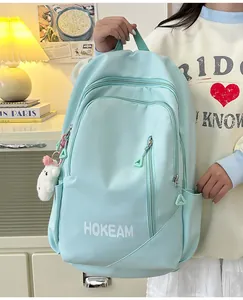 Detail view of mint green school backpack with multi-zipper compartments and cute bear pendant