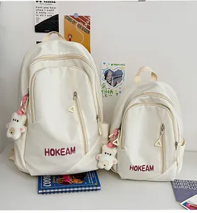 Stylish cream white minimalist student backpacks shown in two sizes with cute bear