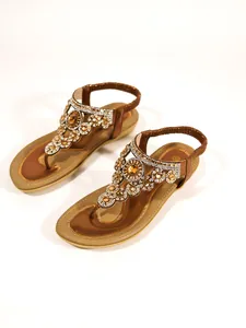 Detailed view of bronze flat sandals featuring intricate rhinestone flower patterns