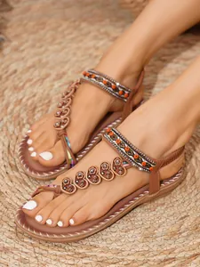 Close-up of bohemian flat sandals with ethnic beads and heart leather details