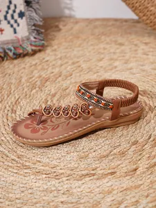 Close-up of Bohemian flat sandals with intricate beading and floral printed insole.