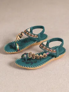 Close-up detail of teal bohemian flat sandals with intricate beadwork and floral patterns