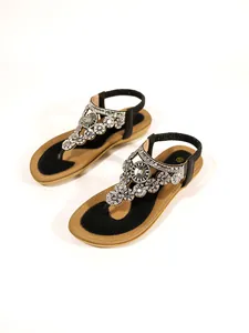 Women's flat T-strap sandals with luxury rhinestone flower embellishments in black and tan.