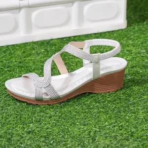 Comfortable silver bohemian wedge sandals with braided straps displayed on green grass
