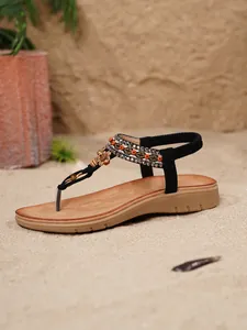 Detailansicht der böhmischen Zehensandalen mit Holzperlen und Strasssteinen auf Sand