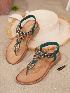 Detailansicht von böhmischen flachen Sandalen mit Strasssteinen und Perlen auf Sand