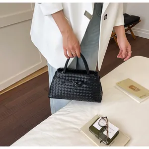 Detailansicht der schwarzen gewebten Handtasche, die vom Modell gehalten wird