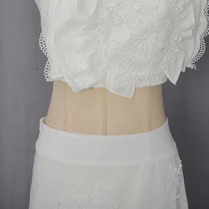 Détail de la broderie en dentelle florale blanche sur l'ensemble jupe et haut de plage.