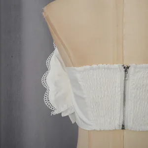 Vue détaillée d'un haut bandeau smocké blanc avec une fermeture éclair et dentelle