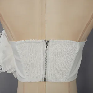 Vue détaillée du dos d'un top bustier blanc froncé avec fermeture à glissière en métal