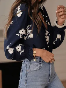 Close-up of white floral embroidery on navy blue bubble sleeve shirt with ruffle cuff.