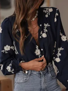 Detail of navy blue blouse with delicate white floral embroidery and puff sleeves.