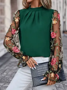 Detail der eleganten dunkelgrünen Bluse mit floral bestickten Netzärmeln.
