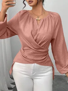 Gros plan sur un chemisier rose à manches longues avec taille nouée et col rond pour femme
