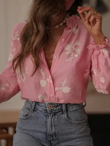 Detail of a pink women's blouse with delicate white floral embroidery and ruffled cuffs