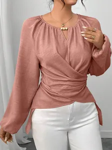 Détail d'un chemisier rose à manches longues avec taille croisée et décolleté perlé élégant