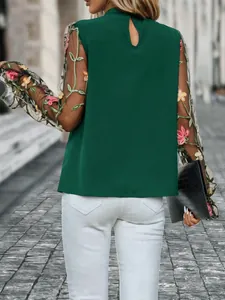 Rückansicht einer eleganten dunkelgrünen Bluse mit floral bestickten Netzärmeln.