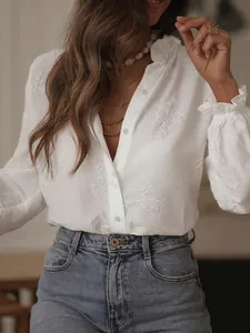 Close-up view of white embroidered shirt with ruffle collar and elegant floral patterns