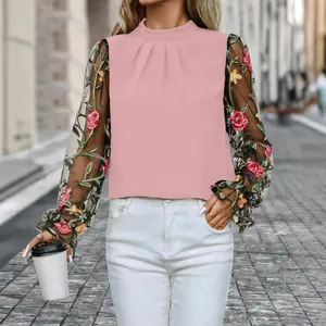 Detailansicht einer rosa Bluse mit floral bestickten Netzhülsen und Stehkragen.