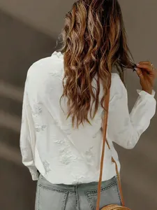 Detailed view of white embroidered blouse with delicate floral patterns and bubble sleeves.
