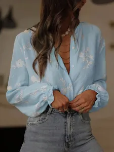 Detailed view of light blue embroidered blouse with white floral patterns and ruffled cuffs