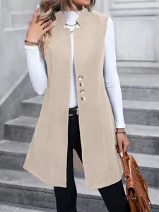 Elegante gilet lungo senza maniche beige, con top bianco a collo alto e borsa in pelle marrone.
