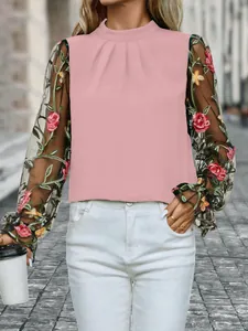 Detailansicht der rosa Bluse mit schicker Blumenstickerei auf schwarzen Netzärmeln