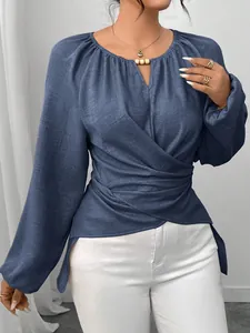 Détail d'une élégante blouse bleue à manches longues avec une taille croisée chic.
