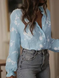 Detail view of light blue embroidered blouse with elegant floral patterns and bubble sleeves.