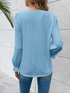 Detail view of the light blue long-sleeve blouse with ruffle cuffs and textured fabric.