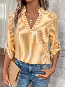 Détail de la blouse à rayures jaunes col en V avec poche et manches retroussées.