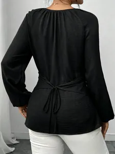 Vue arrière d'une blouse noire à manches longues avec un nœud élégant à la taille